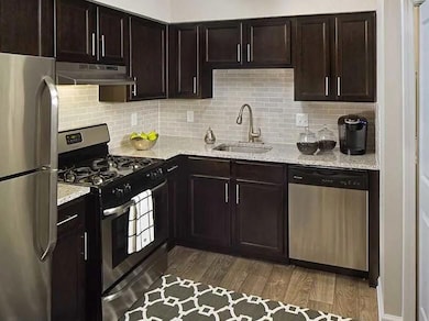 Kitchen featuring light stone countertops, dark br
