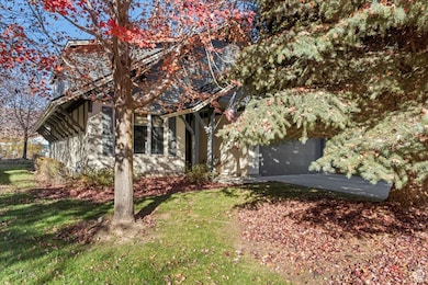 View of property hidden behind natural elements with a garage, driveway, and a front yard
