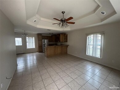 Kitchen featuring a tray ceiling, light tile patterned flooring, freestanding refrigerator, a ceiling fan, and open floor plan