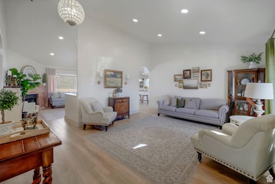 Living room featuring recessed lighting, arched walkways, light wood-type flooring, and high vaulted ceiling