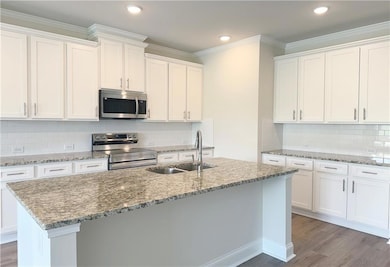 Kitchen featuring a sink, white cabinets, wood fin