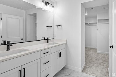 Bathroom with double vanity, a spacious closet, and light marble finish flooring