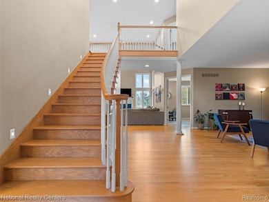 Staircase with recessed lighting, wood finished floors, ornate columns, and a towering ceiling
