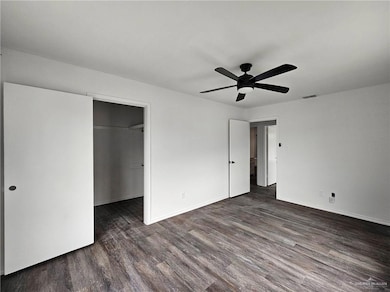 Unfurnished bedroom with wood finished floors, a spacious closet, a ceiling fan, and a closet