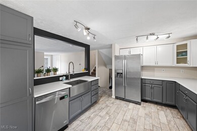Kitchen with gray cabinetry, stainless steel appliances, a textured ceiling, wood tiled floors, and glass insert cabinets