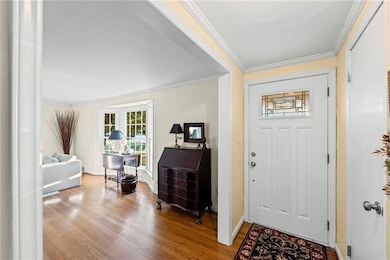 Entrance foyer with ornamental molding, wood finished floors, and healthy amount of natural light