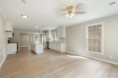 Kitchen with white cabinetry, ornamental molding, a sink, a ceiling fan, and appliances with stainless steel finishes