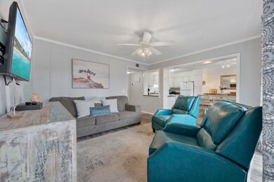 Living room featuring ornamental molding, wood finished floors, a ceiling fan, and a decorative wall