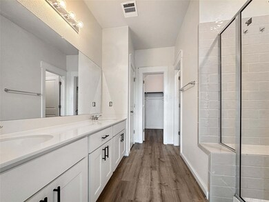 Bathroom with double vanity, a shower stall, wood