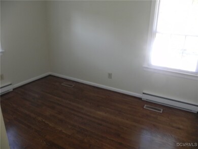 Unfurnished room featuring a baseboard radiator and dark hardwood / wood-style floors