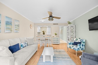 Living area with crown molding, wood finished floors, and ceiling fan