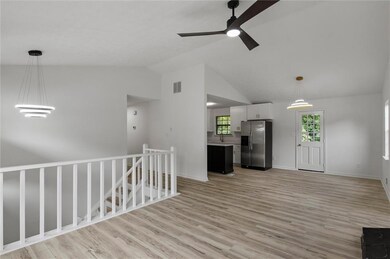 Unfurnished living room with ceiling fan, lofted ceiling, light wood-style flooring, a sink, and baseboards