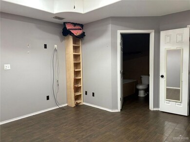 Unfurnished bedroom featuring dark wood-style flooring, baseboards, and ensuite bath