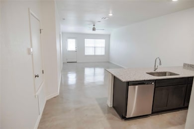 Kitchen with finished concrete flooring, dishwasher, light stone counters, ceiling fan, and open floor plan