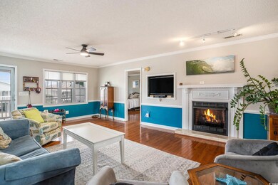 Living room with wood finished floors, a textured ceiling, track lighting, crown molding, and a lit fireplace