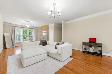 Living room featuring light wood finished floors, ornamental molding, a chandelier, and ceiling fan