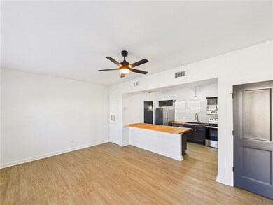 Kitchen with butcher block countertops, a peninsula, pendant lighting, light wood-style floors, and stainless steel appliances