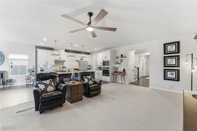 Living area with a ceiling fan, light carpet, and recessed lighting