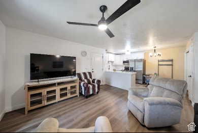 Living room with wood finished floors, a chandelier, ceiling fan, and a textured ceiling