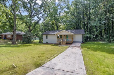 View of front facade featuring covered porch, driveway, and a front yard