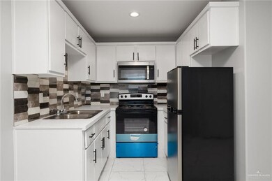 Kitchen featuring stainless steel appliances, a sink, light countertops, backsplash, and recessed lighting