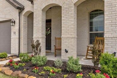 Extended covered front porch with lush landscaping.