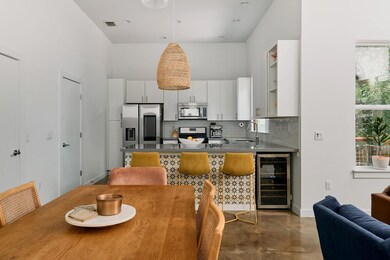Kitchen featuring appliances with stainless steel finishes, wine cooler, finished concrete floors, tasteful backsplash, and white cabinets