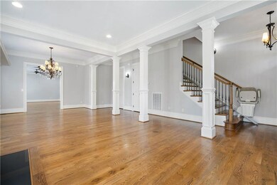 Unfurnished living room with a chandelier, wood finished floors, stairs, ornamental molding, and recessed lighting