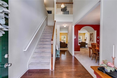 Entrance foyer with a towering ceiling, stairs, arched walkways, and wood finished floors