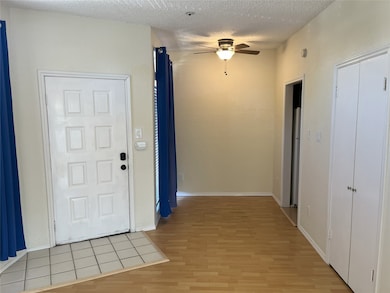 Foyer with light wood finished floors, a ceiling fan, and a textured ceiling