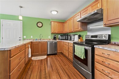 Kitchen with stainless steel appliances, under cabinet range hood, light countertops, and dark wood finished floors