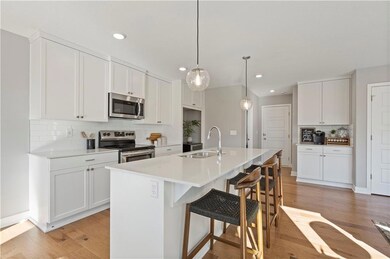 Kitchen featuring decorative backsplash, a breakfast bar, appliances with stainless steel finishes, white cabinetry, and a kitchen island with sink