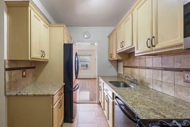 Kitchen featuring light stone counters, black appliances, light tile patterned floors, and tasteful backsplash