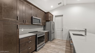 Kitchen with dark brown cabinets, vaulted ceiling