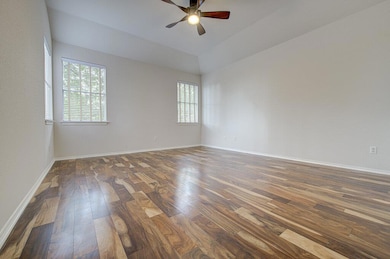 Spare room with dark wood-type flooring, a ceiling fan, and vaulted ceiling