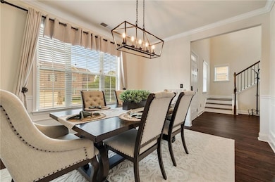Dining room featuring a chandelier, dark wood-type flooring, crown molding, stairway, and baseboards