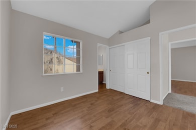 Unfurnished bedroom featuring lofted ceiling, wood finished floors, and a closet