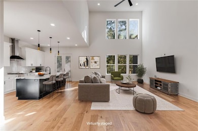 Living area with recessed lighting, light wood-style flooring, and a towering ceiling