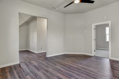 Empty room featuring ceiling fan and dark hardwood / wood-style flooring