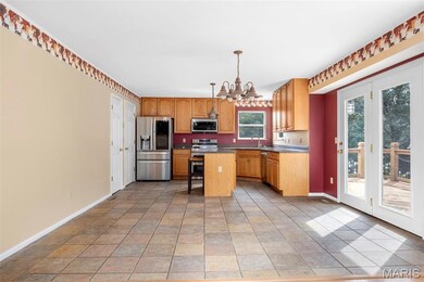 Kitchen featuring appliances with stainless steel finishes, a chandelier, a kitchen island, pendant lighting, and a breakfast bar area