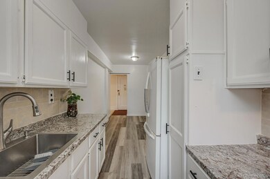 Kitchen with tasteful backsplash, freestanding refrigerator, and white cabinets