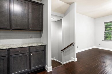 Kitchen featuring dark wood-style floors, tasteful backsplash, dark brown cabinets, and light stone countertops