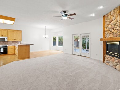 Unfurnished living room featuring a fireplace, ceiling fan, light colored carpet, a chandelier, and light wood finished floors