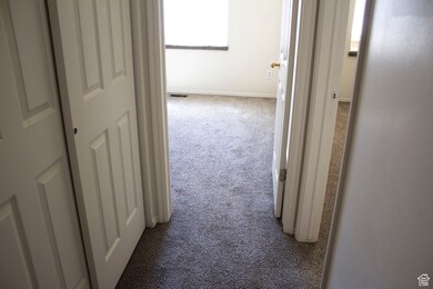 Corridor with baseboards, visible vents, and carpet floors
