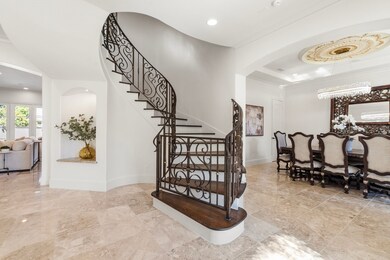 The grand foyer makes a statement with soaring 19’ ceilings and a custom staircase railing.