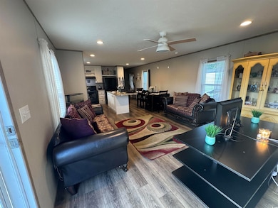 Living room with wood finished floors, ceiling fan, and recessed lighting