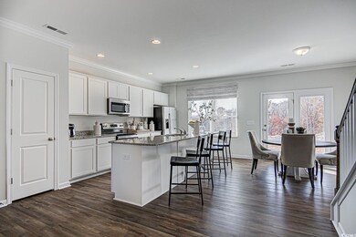 Kitchen with dark wood-style flooring, a breakfast bar area, stainless steel appliances, and a kitchen island with sink