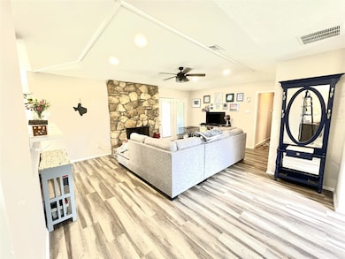 Living area featuring light wood-style flooring, a fireplace, and a ceiling fan