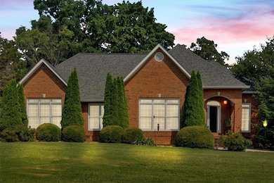 View of front facade with brick siding, a front lawn, and roof with shingles