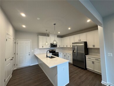 Kitchen featuring appliances with stainless steel finishes, tasteful backsplash, hanging light fixtures, and dark wood-type flooring